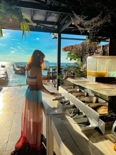 a woman standing at a counter in front of the ocean at Lipe Power Beach Resort in Ko Lipe