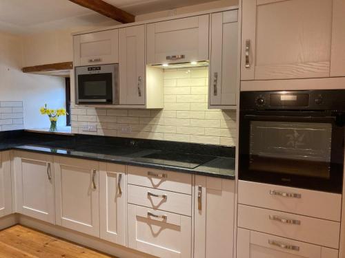 a kitchen with white cabinets and black counter tops at Wheal Kitty nr Truro in Truro