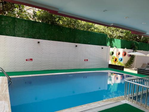 a swimming pool with a green and white wall at Twin Apart Hotel in Alanya