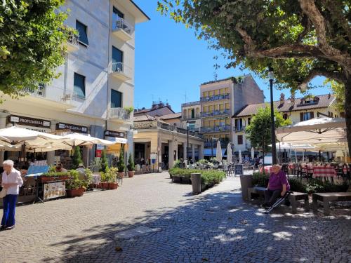 a town square with people sitting on benches and umbrellas at Al Dolce Vita in Stresa