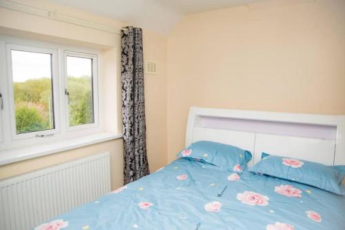 Schlafzimmer mit einem Bett mit blauer Bettwäsche und einem Fenster in der Unterkunft Immaculate 3-Bed House in Dudley in Dudley