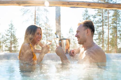 a man and a woman in a hot tub at Hotel & Spa Resort Järvisydän in Rantasalmi