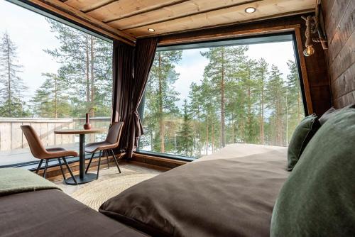 a bedroom with a bed and a table and a large window at Hotel & Spa Resort Järvisydän in Rantasalmi