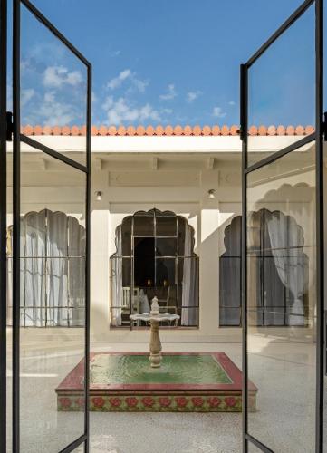 a view through two glass doors of a building with a fountain at Gaj Kesri by 7Apple Resorts in Bikaner