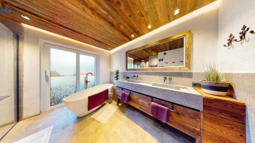 un bagno con una grande vasca e una grande finestra di PitzPlus Appartements a Sankt Leonhard im Pitztal