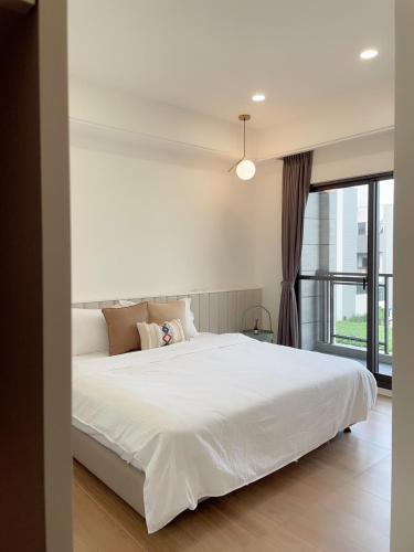 a bedroom with a large white bed and a window at Muzhu B&B in Yilan City