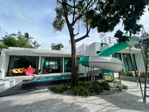 a house with a slide next to a tree at 168 Garden Pool Villa in Nong Prue