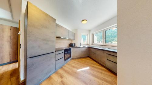 a kitchen with wooden cabinets and a large window at PitzPlus Appartements in Sankt Leonhard im Pitztal