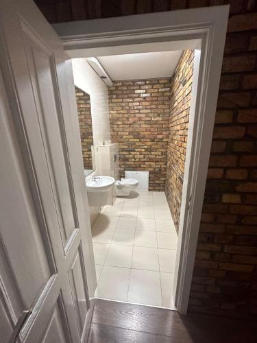 La salle de bains est pourvue de toilettes et d'un mur en briques. dans l'établissement Mieszkanie Centrum 140 m2, à Gorzów Wielkopolski