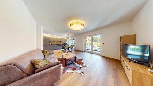 a living room with a couch and a flat screen tv at PitzPlus Appartements in Sankt Leonhard im Pitztal