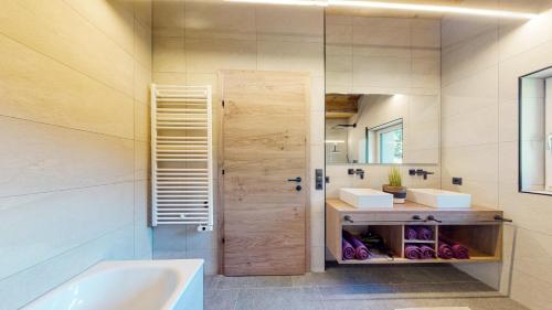 a bathroom with a tub and a sink and a door at PitzPlus Appartements in Sankt Leonhard im Pitztal