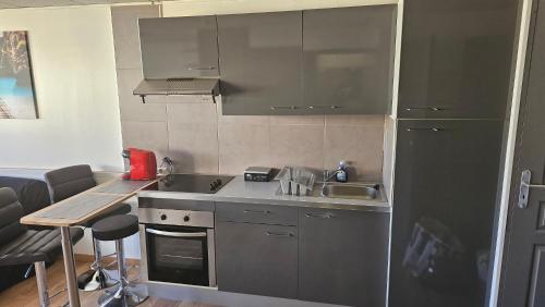 - une cuisine avec des placards gris, un évier et une table dans l'établissement Grand studio climatisé, à La Ciotat