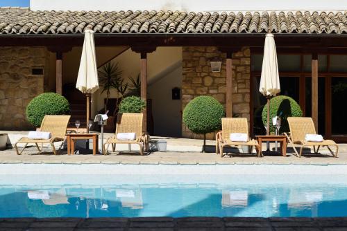 un grupo de sillas y sombrillas junto a una piscina en Hotel Puerta de la Luna en Baeza