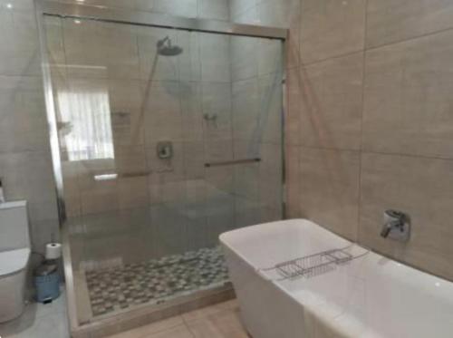 een badkamer met een douche, een bad en een toilet bij 6 Sleeper Villa Clarens Golf Estate in Clarens