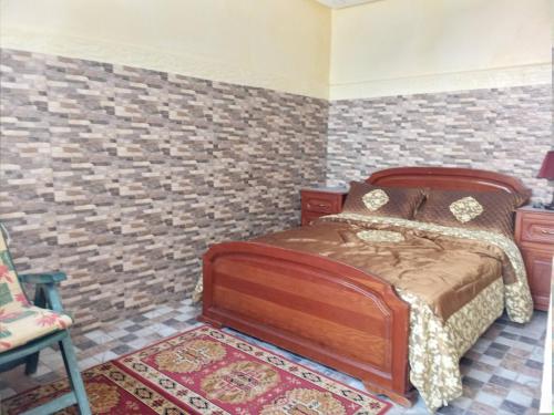 a bedroom with a bed and a brick wall at Villa in Oulad Akkou