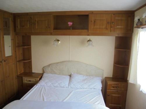 a bedroom with a bed and wooden cabinets at Sealands : Arronbrook:- 6 Berth, Access to the beach, Close to site entrance in Ingoldmells
