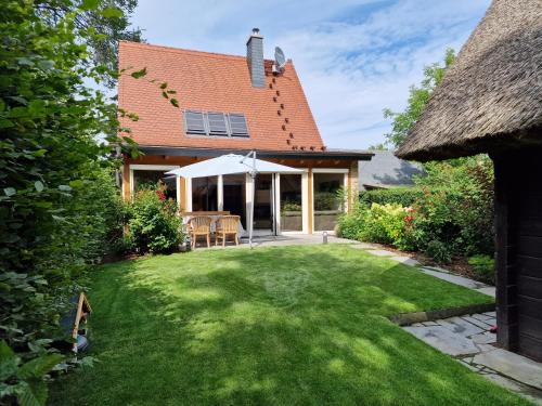 una casa con un patio de césped con una sombrilla blanca en Fließ Paradies mit Blockbohlensauna en Leipe