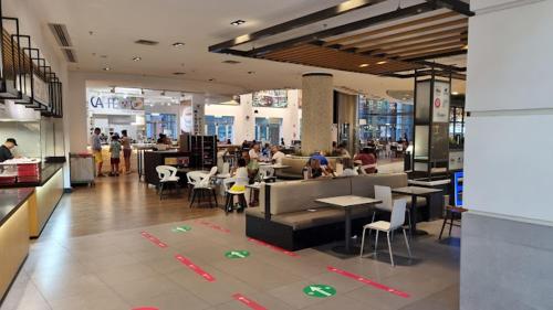 a restaurant with people sitting at tables in a cafeteria at FIUMARA MALL Apartment in Genoa