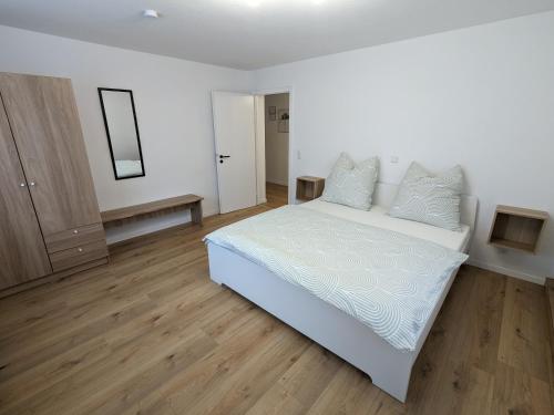 a bedroom with a white bed and a wooden floor at Ferienwohnung am Alenberg in Münsingen