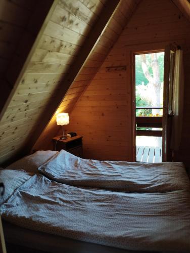 a bed in a wooden room with a window at morska chata in Lubiatowo
