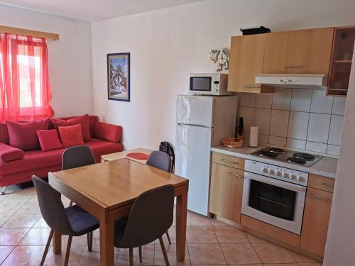 a kitchen and living room with a table and a red couch at Apartman Katarina in Seget Vranjica