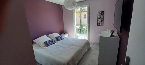une chambre avec un lit aux murs violets et une fenêtre dans l'établissement Villa l ÉCRIN au cœur des alpilles, à Mouriès