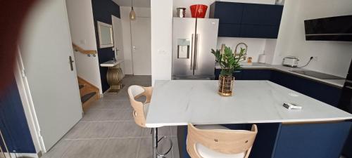 Il comprend une cuisine avec un îlot blanc, des chaises et un réfrigérateur. dans l'établissement Villa l ÉCRIN au cœur des alpilles, à Mouriès