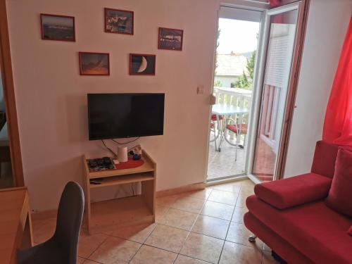 a living room with a flat screen tv and a red couch at Apartman Katarina in Seget Vranjica
