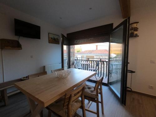 une salle à manger avec une table en bois et un balcon dans l'établissement Apartamentos Sierra y Mar Aldealengua de Pedraza, à Ceguilla