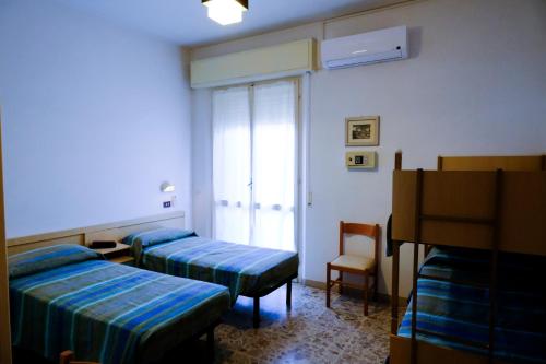 une chambre d'hôpital avec deux lits et une chaise dans l'établissement Hotel Chiara, à Rimini