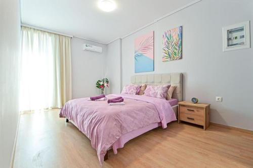 um quarto com uma cama rosa e piso em madeira em Cozy apartment located on Piraeus Port area-(SPETS_D1) em Piraeus