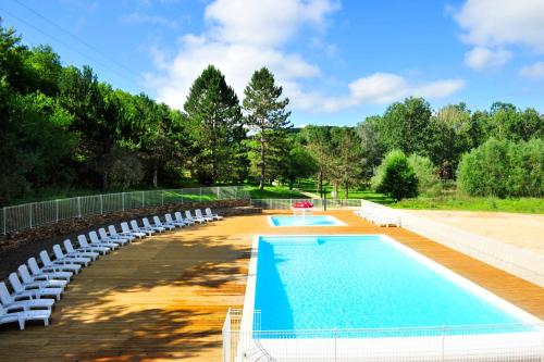 een zwembad met witte stoelen en een zwembad bij Résidence Goélia Les Cottages du Lac in Coly