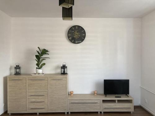 a living room with a tv and a clock on a wall at Apartament w Centrum Malborka in Malbork