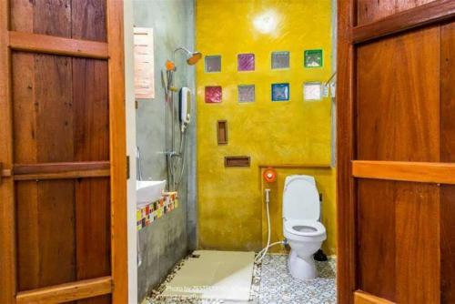 bagno giallo con servizi igienici e lavandino di Na-Rak-O Resort a Chiang Rai