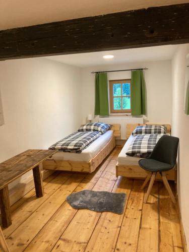 - une chambre avec deux lits, une table et une chaise dans l'établissement Bandltroga, à Murau