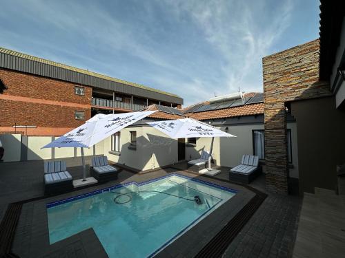 a swimming pool with two umbrellas and a swimming poolvisor at Urban Villas Guest House in Pretoria