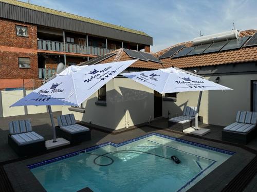 two umbrellas and a swimming pool on a building at Urban Villas Guest House in Pretoria