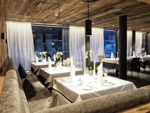 a restaurant with white tables and chairs and windows at Wellness & Naturresort Reischlhof in Wegscheid