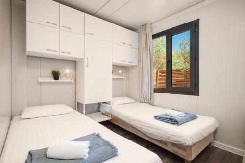 2 camas en una habitación pequeña con ventana en Mobile Homes Vrata Krke, en Lozovac