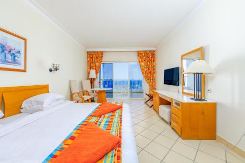 沙姆沙伊赫的住宿－Siva Sharm Resort & SPA - Couples and Families Only，一间卧室配有一张床、一张书桌和一台电视