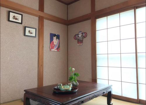 ein Wohnzimmer mit einem Tisch und einem Fenster in der Unterkunft TOMO HOUSE in Taketoyo