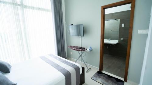 - une chambre avec un lit, un miroir et un lavabo dans l'établissement Quest Colombo Residencies, à Talawatugoda