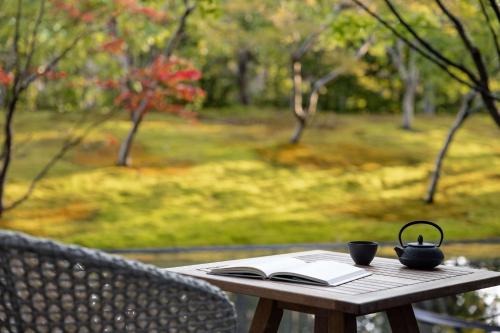 a wooden table with a book and a tea pot on it at Garrya Nijo Castle Kyoto - Banyan Group in Kyoto
