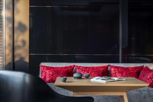 a coffee table in front of a couch with red pillows at Garrya Nijo Castle Kyoto in Kyoto