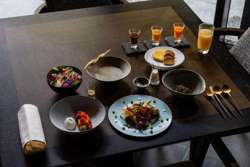 Garrya Nijo Castle Kyoto - Banyan Group في كيوتو: طاولة مع أطباق من الطعام وكؤوس من عصير البرتقال