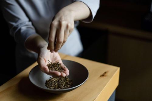 a person holding a bowl of seeds on a table at Garrya Nijo Castle Kyoto in Kyoto