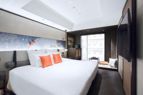 a bedroom with a large white bed with orange pillows at Dhawa Yura Kyoto in Kyoto