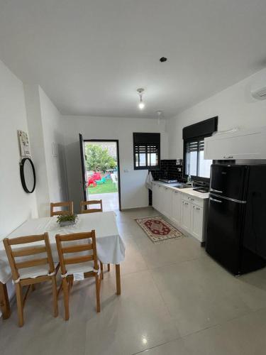 a kitchen with a table and chairs and a refrigerator at סוויטת הגן השקט- סוויטה מושלמת במעלות in Ma'alot Tarshiha