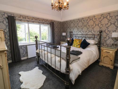 a bedroom with a bed and a window and a chandelier at Bryn Gwynedd in Conwy