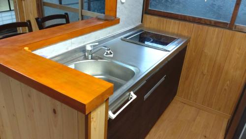 eine Küche mit einer Spüle und einer hölzernen Arbeitsplatte in der Unterkunft Momiji hostel in Minami Aso